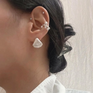 Silver shell-shaped stud earrings and pearl ear cuff set shown on a model