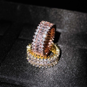 Elegant rose gold and gold rings with sparkling rectangular zircons on a dark background