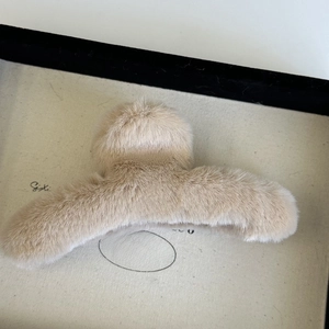 Top view of beige plush claw clip with soft faux fur texture for winter hairstyling