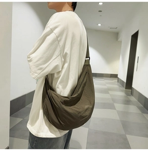 Vue latérale macro d'un grand sac croissant en nylon vert olive porté par un mannequin