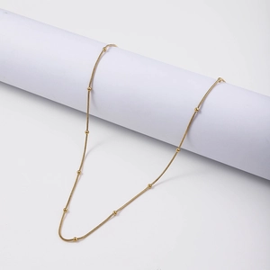 Detail of 18K gold plated stainless steel snake chain with small round beads on white background