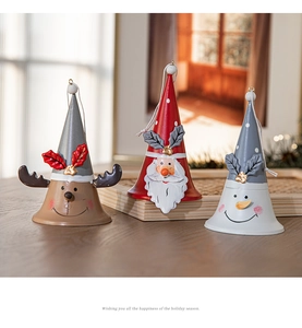 Three painted metal Christmas bells featuring Santa, elk, and snowman on wood