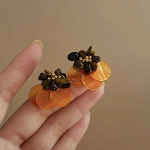 Close-up of vintage flower earrings with brown tiger eye petals and orange shell beads