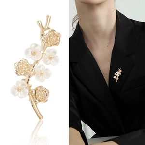 Elegant gold flower branch brooch shown in studio shot and worn on a black blazer lapel