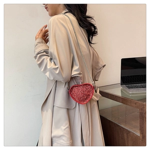 Side view of red sequin heart-shaped mini bag with silver chain on a shoulder