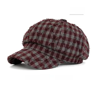 Dettaglio del cappello newsboy a quadri rossi e grigi con bordi sfrangiati retrò
