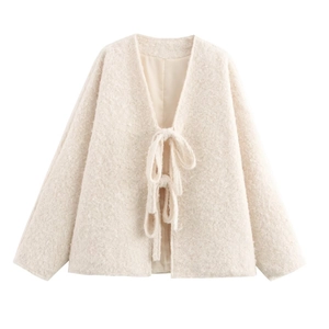Detail shot of the cream-white faux shearling texture and lace-up V-neckline of the cardigan