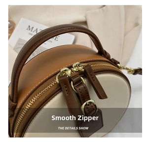Detail of premium gold-tone dual zippers and bicolor leather texture on a round bag