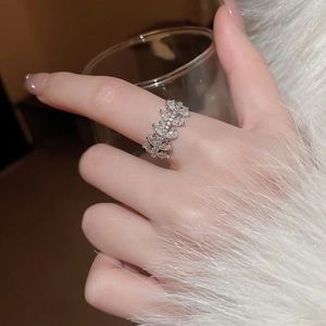 Detail of silver marquise zircon snowflake ring on model holding a glass cup