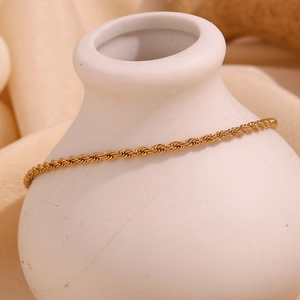 Detailed view of an 18K gold-plated 2mm twisted rope anklet on a white vase