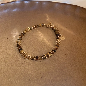 Macro shot of tiger eye stone beads with golden stainless steel accents on a ceramic tray