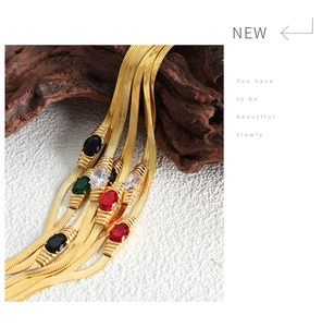 Macro detail of gold snake chains featuring multi-colored oval gemstones and white zircons