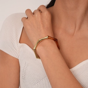 Détail du bracelet géométrique en acrylique ambre et métal doré avec design de bambou