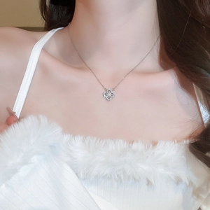 Detailed view of silver clover necklace with sparkling zircons on model neck