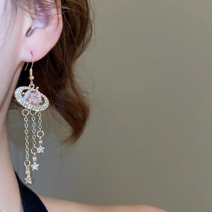 Macro shot of gold tassel earrings with pink star pendant and sparkling crystals