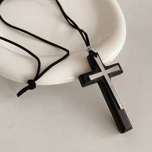 Detail of double cross pendant crafted from black wood and silver metal on leather cord