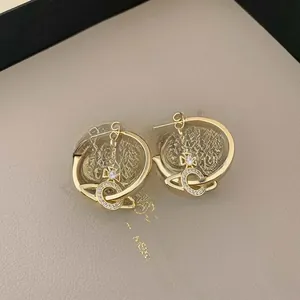 Detailed close-up of golden C-shaped hoop earrings featuring a zircon-encrusted orb pendant
