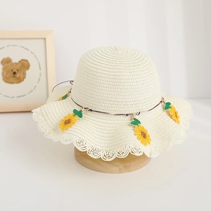 Dettaglio cappello di paglia per bambini con pizzo e ricamo girasole su base in legno