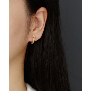 Close-up of gold snake hoop earrings with red gem eyes and detailed scale texture