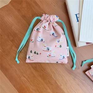 Detail view of pink cotton drawstring bag with cute cartoon duck print on wooden desk
