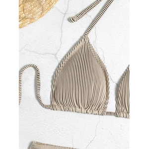 Detail showing the textured rib-knit fabric and halter neck ties of the beige bikini top