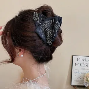 Elegant black satin bow hair clip with silver rhinestones on woman’s head