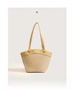 Detail of hand-woven beige straw tote with premium light brown leather straps and trim