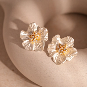 Macro detail of acrylic pearl flower earrings with zircon center and gold plating