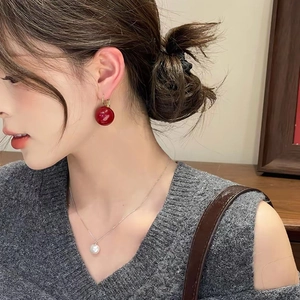 Élégantes boucles d'oreilles boules rouges en résine portées par un mannequin en pull gris