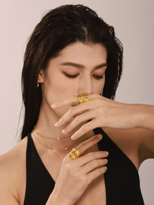 Detailed view of layered pearl necklaces and a hollow wide gold ring on a model