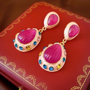 Detailed macro view of vintage gold earrings with rose pink teardrop crystals and jewels