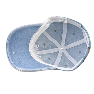 Detail view of washed denim baseball cap featuring internal cotton sweatband and Paris embroidery