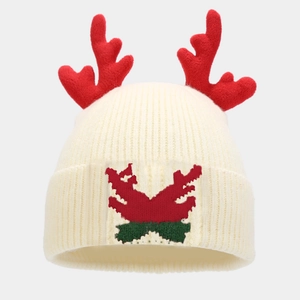 Close-up of cream knitted beanie featuring 3D red reindeer antlers and festive pattern