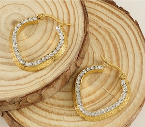 Close-up of 18K gold-plated hoop earrings with sparkling crystals and Greek key pattern