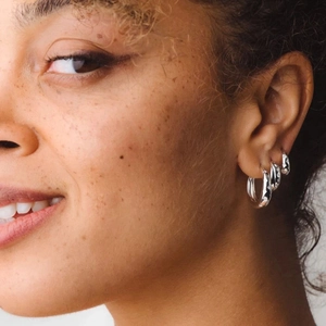 Three sizes of S925 sterling silver hoop earrings with micro-inlaid star accents on model