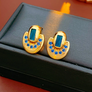 Gros plan de boucles d'oreilles dorées en U avec pierres bleu marine sur écrin