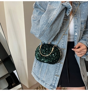 Close-up of sparkling dark green sequins and golden ring handle on a luxury evening clutch