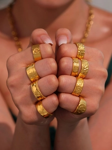 Close-up of chunky gold-plated rings with various embossed patterns for women