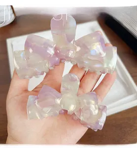 Detail view of large marble texture acetate bow hair claw clip set with pearly finish