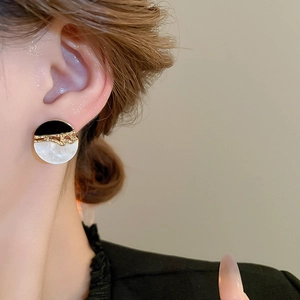 Détail des boucles d'oreilles géométriques en résine bicolore noir et blanc sur un mannequin
