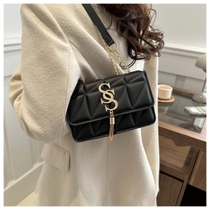 Detail of black quilted crossbody bag with gold chain strap and stylish tassel charm