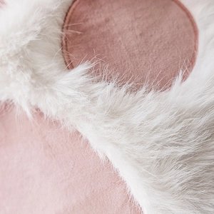 Nordic cat paw cushion with white faux fur and pink woven fabric texture in a close-up view