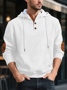 Dettaglio felpa con cappuccio in maglia bianca con patta a bottoni e toppe marroni