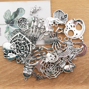 Flat lay of assorted silver Halloween metal charms like skulls and bats on a wood table