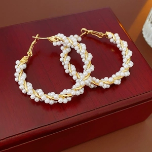 Detailed view of woven pearl hoop earring on a luxury vintage wooden jewelry box