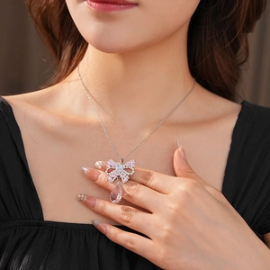 Detail of silver bow necklace with pink teardrop crystal and sparkling zircon stones