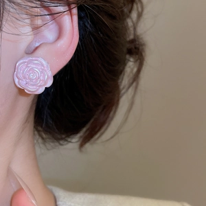 Close-up of elegant pink pearl rose earrings worn on ear showing floral petal details