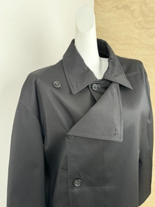 Detail view of black double-breasted short trench coat with classic lapels on a mannequin