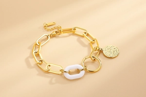 Vue détaillée d'un bracelet chaîne en or avec anneau émail blanc et pendentif pièce martelée