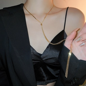 Close-up of a long golden Y-shaped tassel necklace with sleek snake chain texture